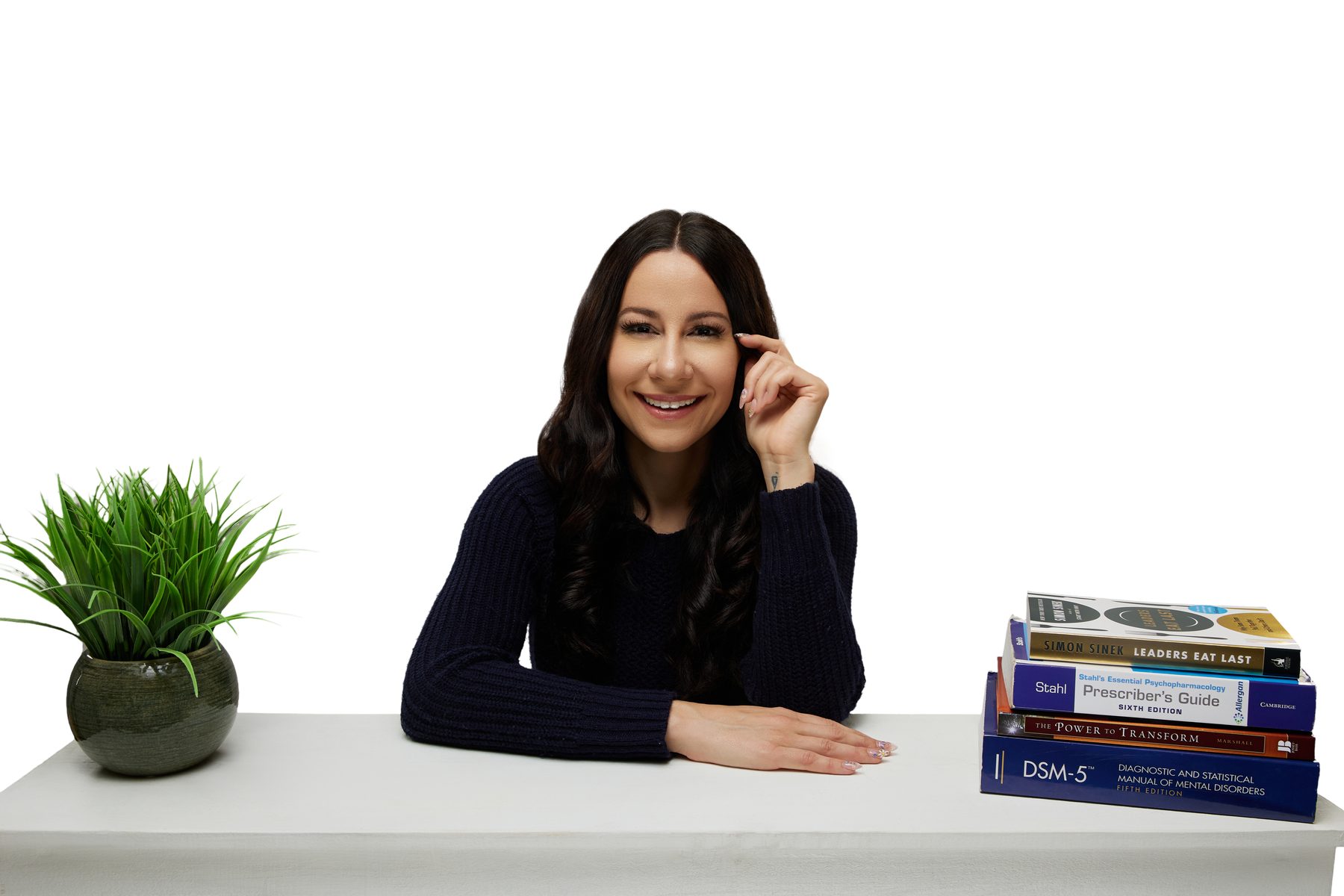 Bryanna Baptiste seated at her desk with psychiatry books, smiling